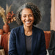 A diverse, smiling person in a professional headshot against a warm-toned background.